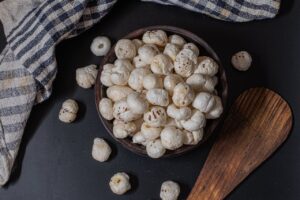 A rustic bowl filled with puffed lotus seeds on a black background, perfect for snacks.